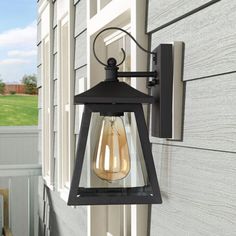 an outdoor wall light on the side of a house with grass in the back ground