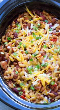 a crock pot filled with macaroni and cheese, beans, green onions