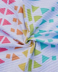 an image of a colorful quilt that is on the ground with it's fabric pulled back