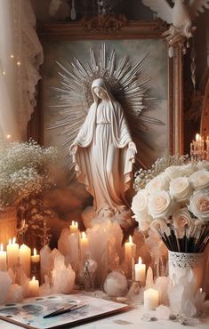 a table topped with lots of candles next to a statue and vase filled with flowers