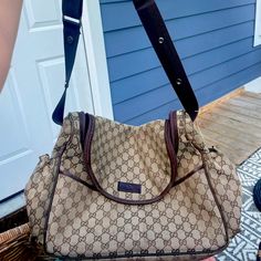 a brown and black handbag sitting on top of a wooden floor next to a door