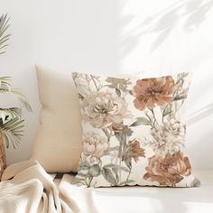 a flowered pillow sitting on top of a white couch next to a potted plant