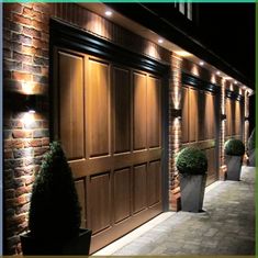 an image of a building that has lights on the side of it and plants in pots outside