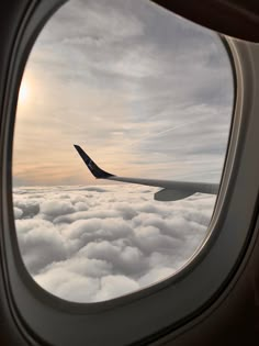 an airplane wing is seen through the window as it flies over clouds in the sky