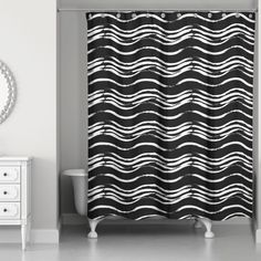 a black and white shower curtain with wavy lines on it in a bathroom next to a mirror