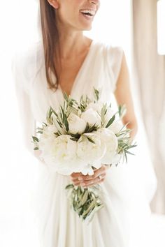 a woman holding a bouquet of white flowers