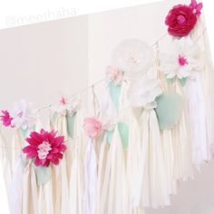 some pink and white flowers are hanging from a string