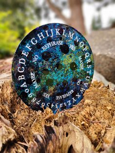 an old button is sitting on top of some wood and leaves in the woods with trees in the background