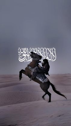 a man riding on the back of a horse across a sandy field under a cloudy sky