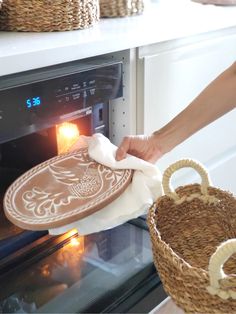 a person is cleaning an oven with a cloth and a basket in front of it