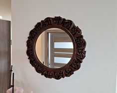 a mirror hanging on the wall above a sink in a room with white walls and wood trimmings