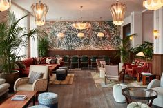 a living room filled with lots of furniture next to a wall covered in plants and hanging lights