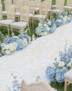 an outdoor ceremony with blue and white flowers on the aisle, along with rows of chairs