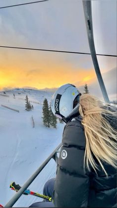 a woman riding on the side of a ski lift at sunset or dawn with her hair blowing in the wind