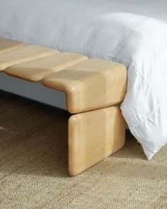 a bed with a white comforter and two wooden benches