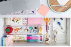 an open drawer with various office supplies on it and a laptop in the bottom right corner