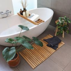 a bathtub with plants and towels on the floor