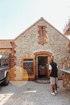 a man standing in front of a brick building with a truck parked next to it