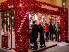 people standing in front of a store decorated with red and white christmas decorations, including candy canes