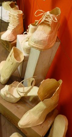 there are many pairs of shoes that are sitting on the table together in front of an orange wall