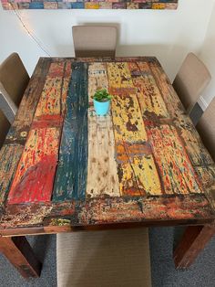 a wooden table with a potted plant sitting on it's top and chairs around it