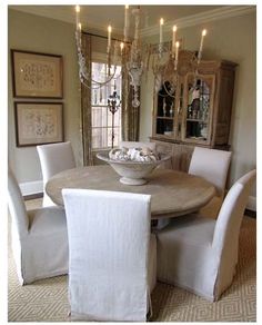 a dining room table with white chairs and chandelier