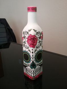 a glass bottle with a skull painted on it sitting on top of a black table