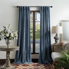 a living room filled with furniture and a large window covered in blue drapes