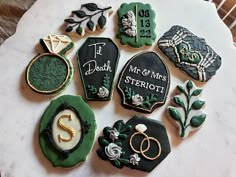 some decorated cookies are sitting on a white tablecloth with green and gold decorations around them