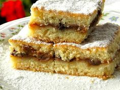 three pieces of cake on a plate with powdered sugar and flowers in the background