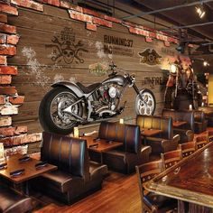 a motorcycle is hanging on the wall in a restaurant with wooden tables and brown leather chairs