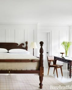 a wooden bed sitting next to a table with a lamp on it's headboard