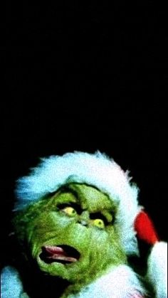 the grinch is wearing a santa hat and holding a cell phone to his ear