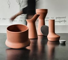 three clay vases sitting on top of a table next to a wall mounted planter