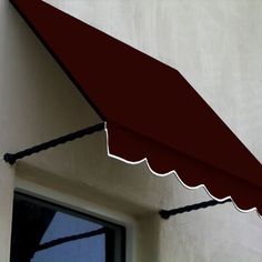 a red awning hanging from the side of a white wall next to a window