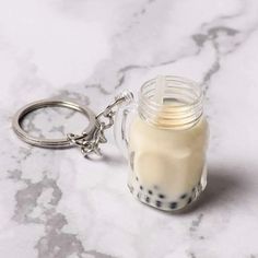 a glass jar filled with milk sitting on top of a marble counter next to a metal keychain