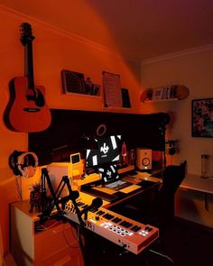 an orange room with guitars and other musical equipment on the desk, along with headphones