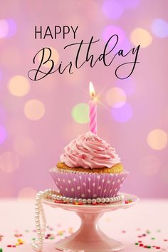 a cupcake with pink frosting and a lit candle on top is sitting on a cake plate