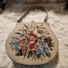 a handbag with flowers painted on it sitting on a white furnishing area