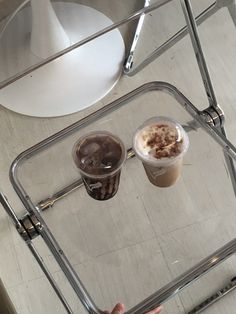 two cups of coffee sitting on top of a glass table