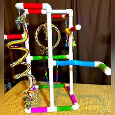 a toy made out of plastic tubes and ropes on top of a wooden table next to a curtain