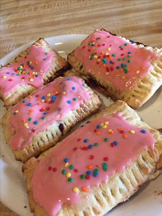 several pastries with pink icing and sprinkles on a plate