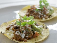 two tacos with meat, cheese and cilantro garnish on them