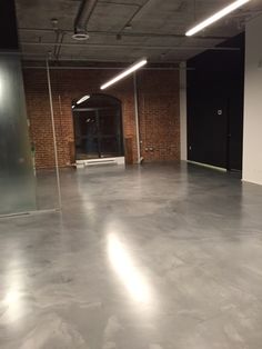 an empty room with brick walls and glass partitions in the center is lit by recessed lights