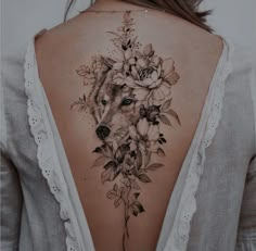 the back of a woman's neck with flowers and a wolf