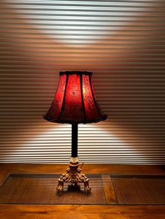 a red lamp sitting on top of a wooden table next to a white and black wall