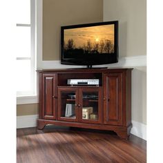 a flat screen tv sitting on top of a wooden entertainment center next to a window