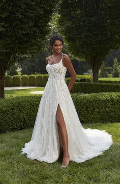 a woman in a white wedding dress standing on grass with her legs crossed and wearing high heels