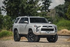 a silver toyota 4runner is parked on the side of the road in front of some trees