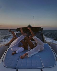 two people sitting on the back of a boat with their feet up in the air